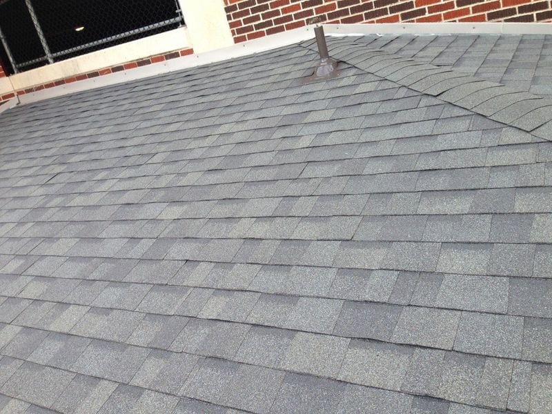a gray roof with a brick building in the background